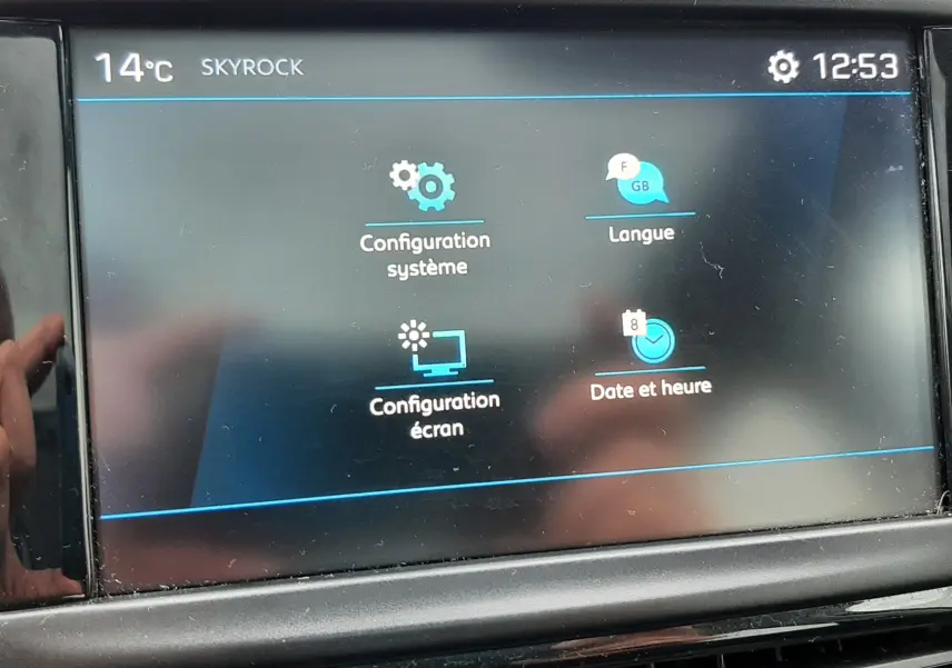 Écran tactile central de la Peugeot 208 bleu nuit 2019 affichant les réglages système, langue, écran et date.