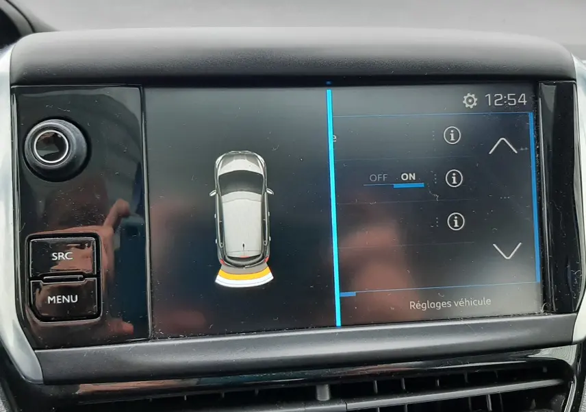 Écran central de la Peugeot 208 2019 montrant l'alerte de proximité arrière avec interface tactile et commandes à gauche.
