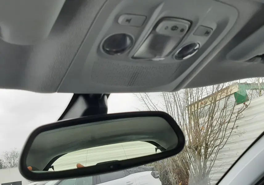 Rétroviseur intérieur d'une Peugeot 208 bleu nuit, vue partielle du plafond et extérieur avec un autre véhicule blanc en arrière-plan.