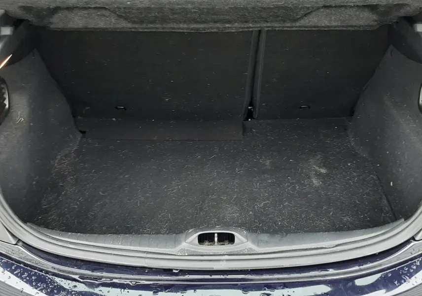 Coffre ouvert vu de l'arrière d'une Peugeot 208 bleu nuit, montrant l'espace de chargement et la plage arrière.