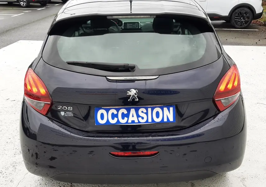 Vue arrière d'une Peugeot 208 bleu nuit 2019 avec feux allumés et plaque "OCCASION" visible.