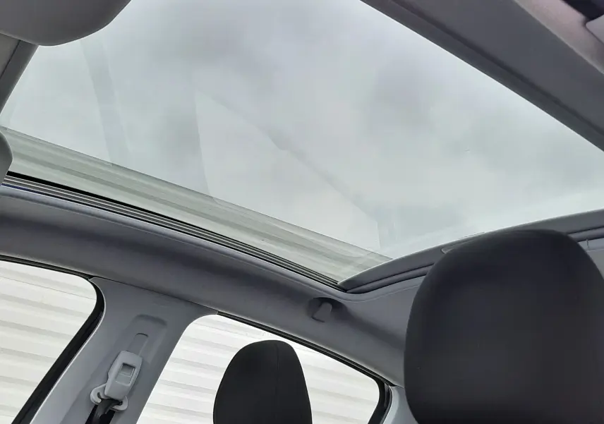 Vue intérieure du toit panoramique et des sièges avant noirs d'une Peugeot 208 bleu nuit 2019.