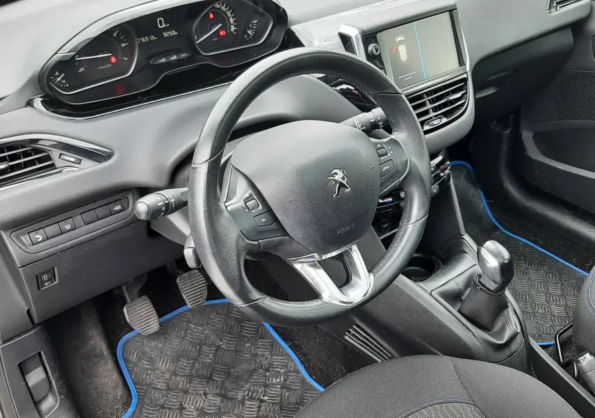 Intérieur avant droit de la Peugeot 208 bleu nuit 2019, volant compact, tableau de bord digital et console centrale avec boîte manuelle.