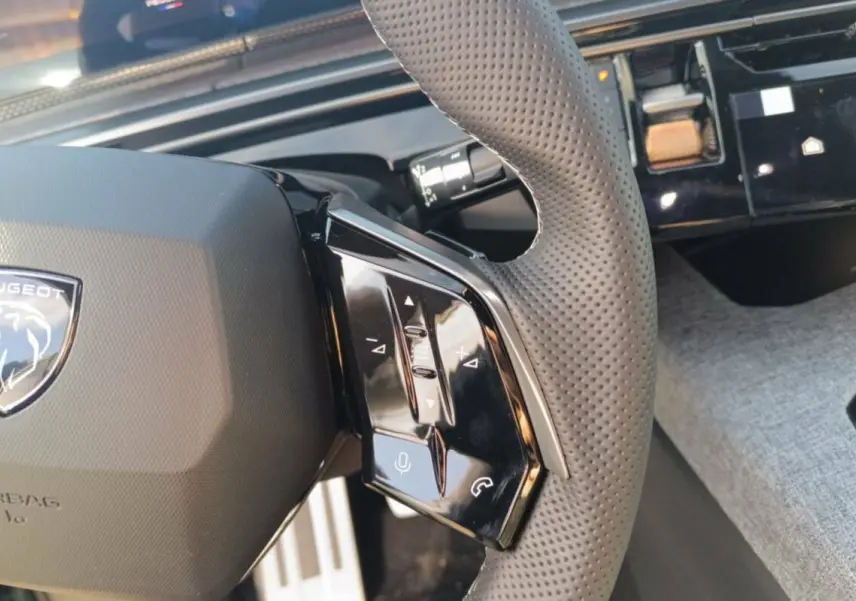 Gros plan sur le volant cuir perforé côté droit du Peugeot 3008 Hybrid 145 GT avec commandes multifonctions.