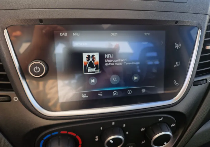 Écran tactile central du tableau de bord de l'Iveco Daily Chassis Cabine 2026 affichant la radio NRJ, avec commandes climatisation en dessous.