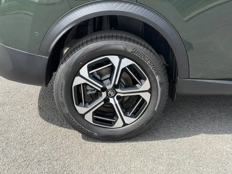 Gros plan sur la roue avant droite du Citroën C3 Aircross Vert Montana avec jante alu au design géométrique noir et argent.