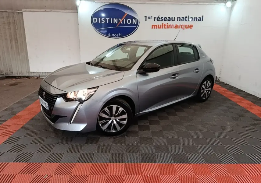 Peugeot 208 gris clair vue 3/4 avant droit, avec feux LED allumés et rétroviseurs noirs contrastants.