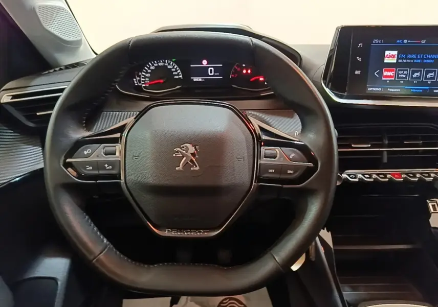Vue rapprochée du volant cuir noir et du tableau de bord numérique de la Peugeot 208 gris clair 2023.