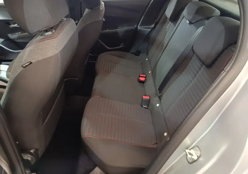 Vue intérieure côté droit sur la banquette arrière noire avec surpiqûres rouges d'une Peugeot 208 gris clair 2023.