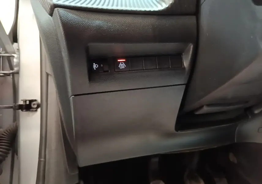 Vue rapprochée du tableau de bord côté conducteur d'une Peugeot 208 gris clair, avec boutons de réglage des phares et assistance au maintien de voie.