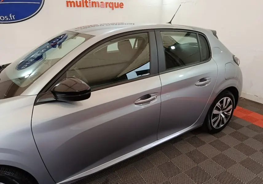 Profil droit de la Peugeot 208 gris clair 2023, mettant en valeur les jantes et les rétroviseurs noirs.