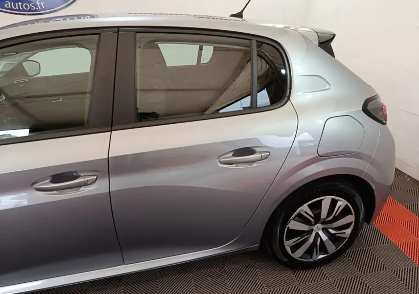 Vue latérale droite d'une Peugeot 208 gris clair, mettant en valeur la porte arrière et la jante au design moderne.