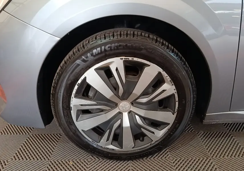 Gros plan sur la roue avant gauche gris clair d'une Peugeot 208 2023 avec jante en alliage au design moderne.