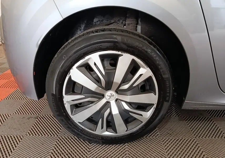 Gros plan sur la roue avant gauche gris clair d'une Peugeot 208 PureTech 100 S&S Active Pack 2023 avec jante stylisée.