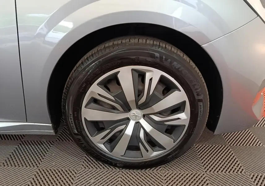 Gros plan sur la roue avant droite gris clair d'une Peugeot 208 2023 avec jante alliage au design moderne.