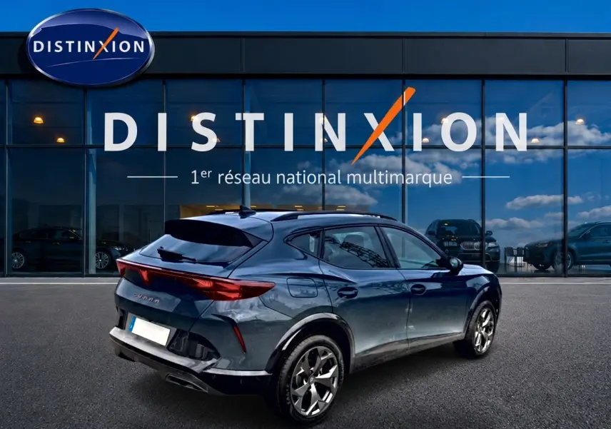 Vue 3/4 arrière droite d'un CUPRA Formentor bleu fjord 2026 avec jantes 18 pouces, garé devant un showroom Distinxion.