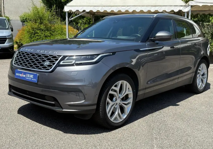 Range Rover Velar gris en vue 3/4 avant droit, avec calandre distinctive et jantes alliage modernes.