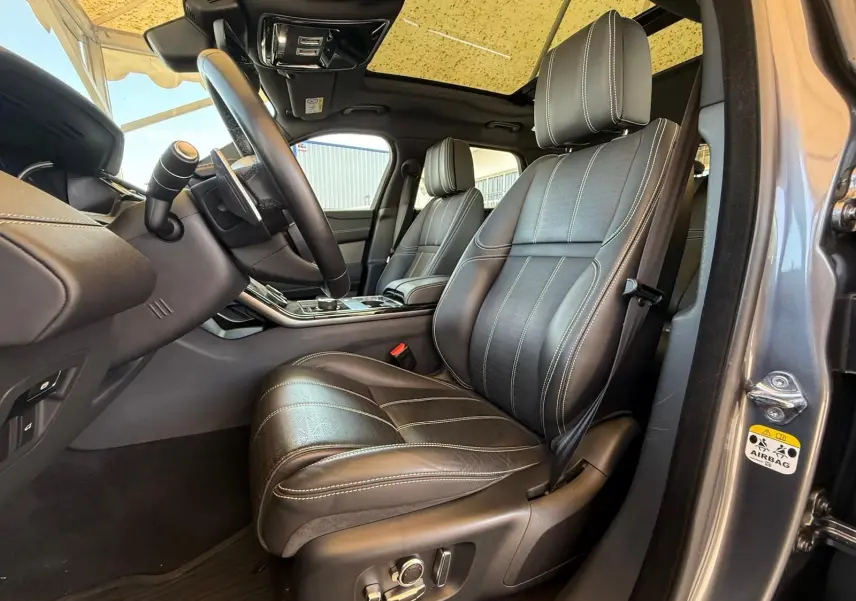 Vue intérieure côté conducteur du Range Rover Velar gris 2019, mettant en valeur les sièges cuir Windsor et le volant multifonction.