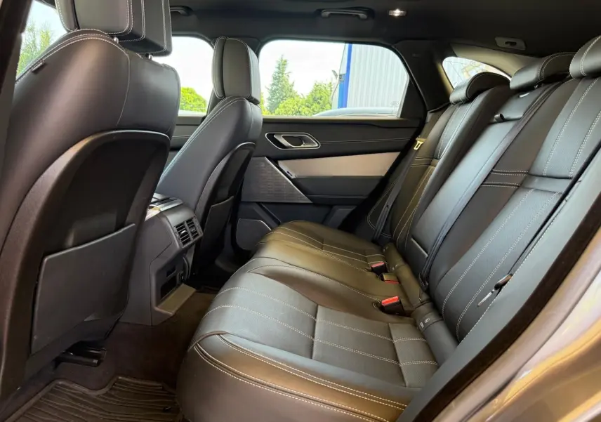Vue latérale intérieure des sièges arrière en cuir noir avec surpiqûres blanches du Range Rover Velar gris 2019.