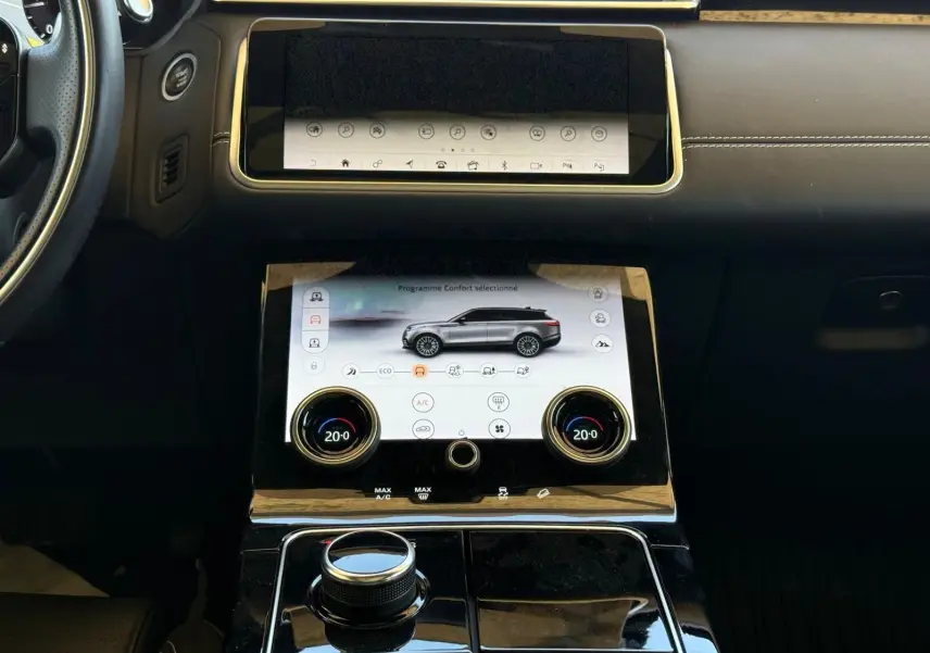 Vue rapprochée du tableau de bord du Range Rover Velar gris, mettant en valeur l'écran tactile central et les commandes de climatisation.