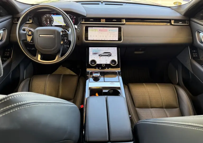Vue intérieure avant du Range Rover Velar 2019, avec tableau de bord en cuir marron et écran tactile central double.