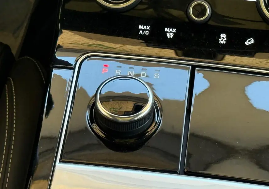 Gros plan sur la molette de sélection de la boîte automatique du Range Rover Velar gris, avec indicateurs lumineux P, R, N, D, S.
