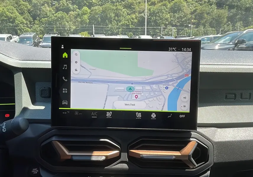 Vue intérieure du tableau de bord du Dacia Duster 2025 avec écran tactile affichant la navigation et aérateurs design.
