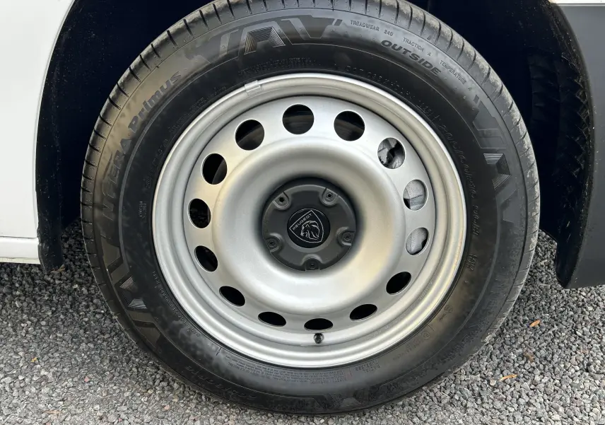 Gros plan sur la roue acier grise avec logo Peugeot d'un fourgon blanc PEUGEOT Partner Fourgon 2025.