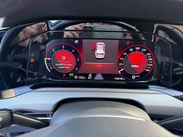 Vue rapprochée du tableau de bord numérique de la Volkswagen Golf VIII gris lunaire, affichant les compteurs et alertes.