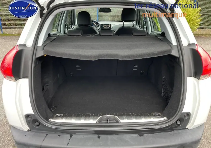 Coffre ouvert vu de l'arrière d'un Peugeot 2008 blanc nacré, montrant l'espace de chargement et la plage arrière.