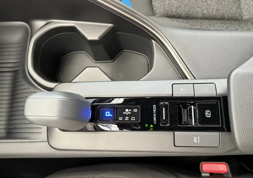 Vue rapprochée de la console centrale du Toyota C-HR blanc 2024, avec levier de vitesse automatique et boutons de mode de conduite.