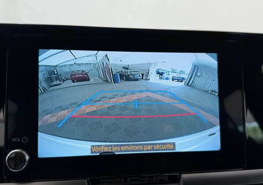 Affichage caméra de recul du Toyota C-HR blanc 2024 montrant l'arrière et le sol avec repères colorés dans un garage.