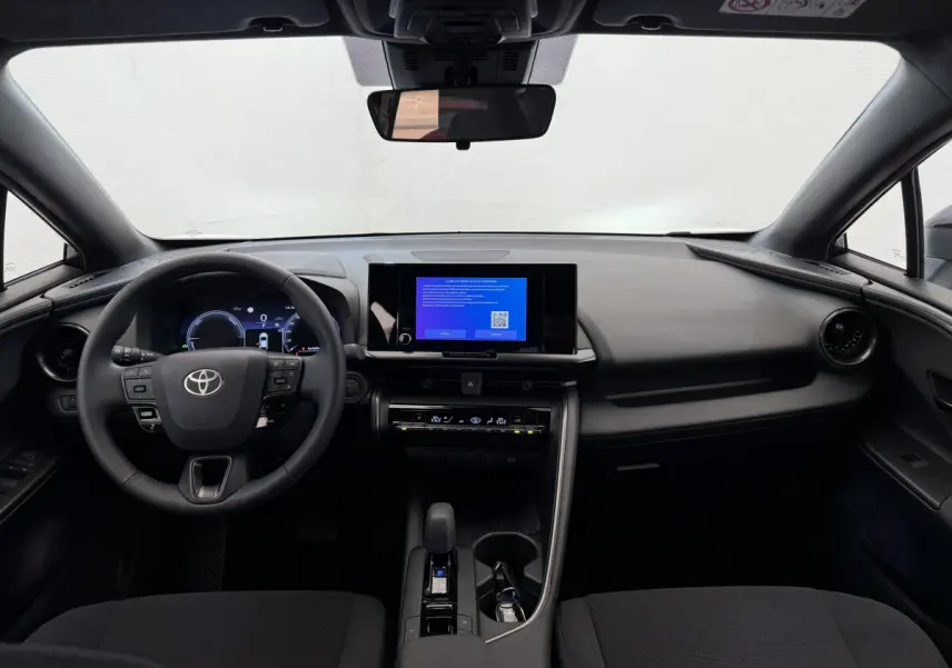 Intérieur noir du Toyota C-HR 1.8 Hybride 2024 vu de face, tableau de bord moderne avec écran tactile central.