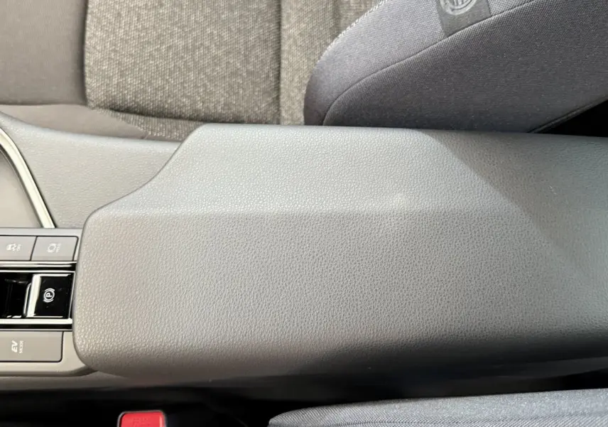 Accoudoir central gris clair en cuir avec commandes électroniques, intérieur du Toyota C-HR 1.8 Hybride 2024 vue de dessus