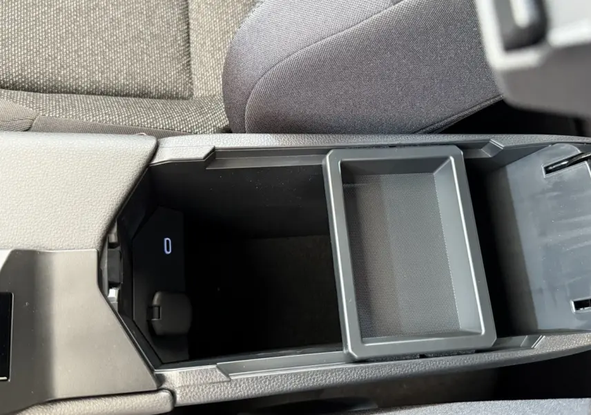 Vue rapprochée de l'accoudoir central ouvert du Toyota C-HR blanc 2024, montrant le rangement intérieur noir.