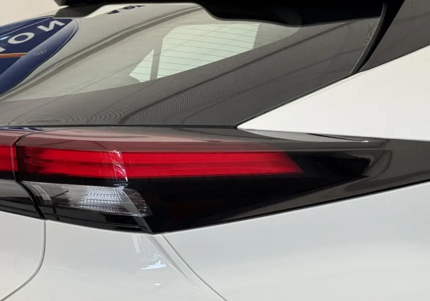 Gros plan sur le feu arrière gauche rouge et blanc du Toyota C-HR 1.8 Hybride blanc 2024, soulignant sa ligne épurée.