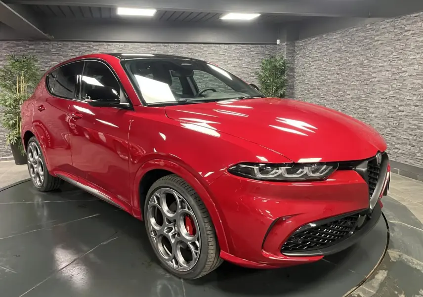 Alfa Romeo Tonale rouge en 3/4 avant droit avec jantes 20 pouces et toit noir dans un showroom.