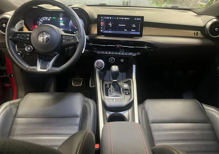 Intérieur de l'Alfa Romeo Tonale 2024 vu de face, avec volant sport cuir noir, tableau de bord digital et console centrale moderne.