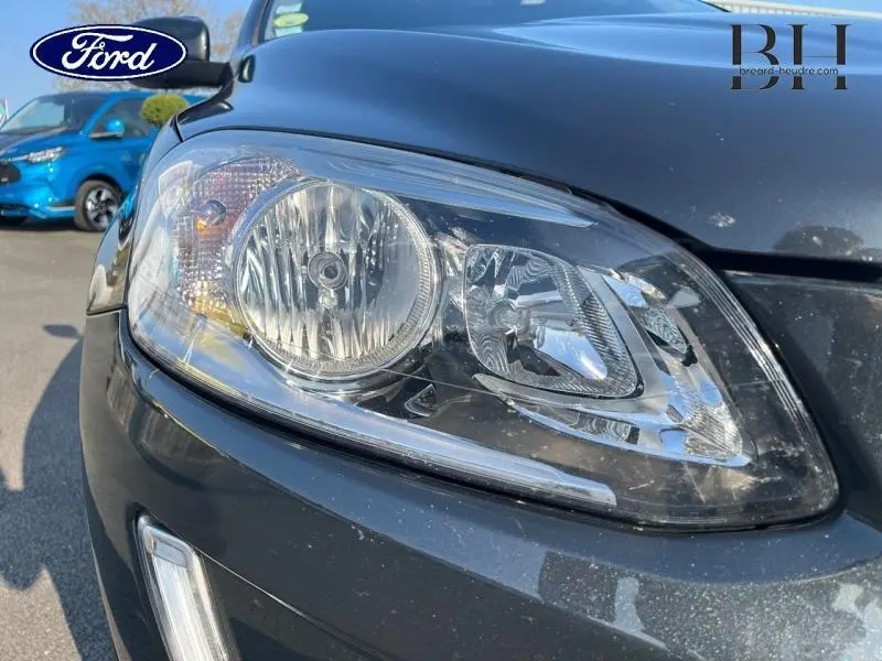 Gros plan sur le phare avant droit du Volvo XC60 gris Savile, mettant en valeur les détails du bloc optique.