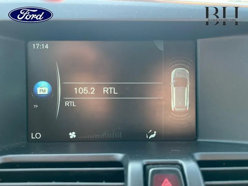 Écran central d’un Ford affichant la radio FM 105.2 RTL et l’alerte de proximité du véhicule en vue de dessus.