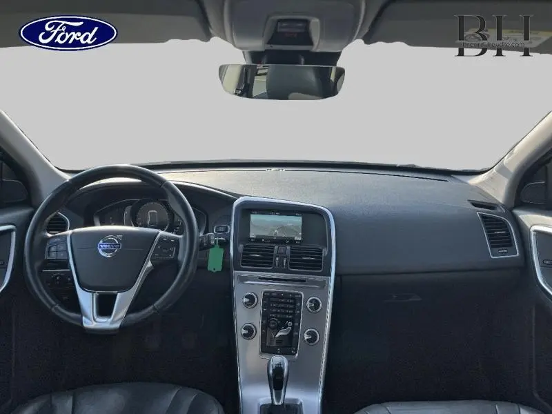 Vue intérieure avant du tableau de bord gris et volant cuir du Volvo XC60 D3 Momentum Business 2016.