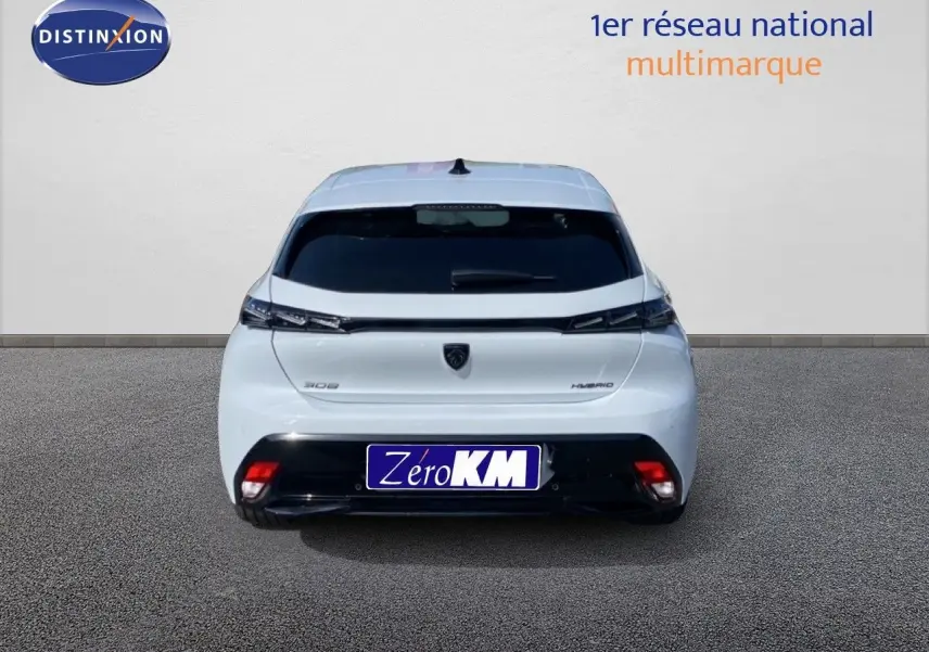 Vue arrière d'une Peugeot 308 blanche Okenite Metal, version hybride 2026, avec feux arrière fins et plaque Zéro KM.