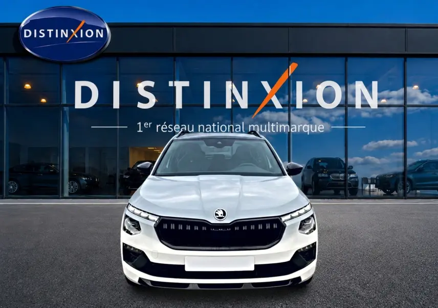 Vue frontale d'un Skoda Kamiq blanc nacré avec calandre noire et toit panoramique, devant une vitrine Distinxion.
