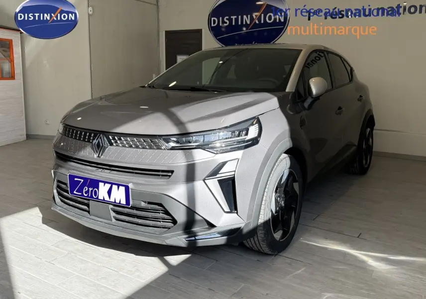 Vue 3/4 avant du Renault Captur 2025 gris Cassiopée métal avec toit gris, en intérieur showroom, mettant en valeur ses optiques LED et jantes biton.
