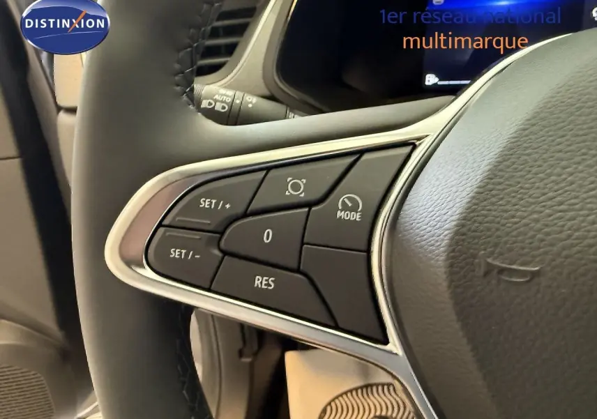 Gros plan sur les commandes au volant à gauche du Renault Captur gris Cassiopée, mettant en valeur les boutons de réglage.