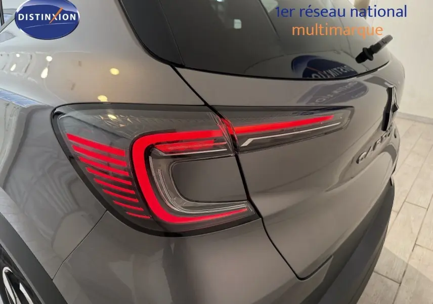 Gros plan sur le feu arrière gauche rouge d’un Renault Captur gris cassiopée métal avec toit gris, vue arrière en intérieur.