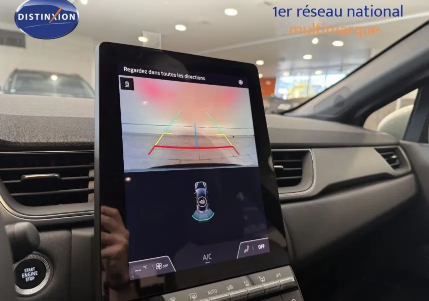 Vue intérieure du tableau de bord du Renault Captur 2025, écran tactile affichant la caméra de recul et commandes climatisation.