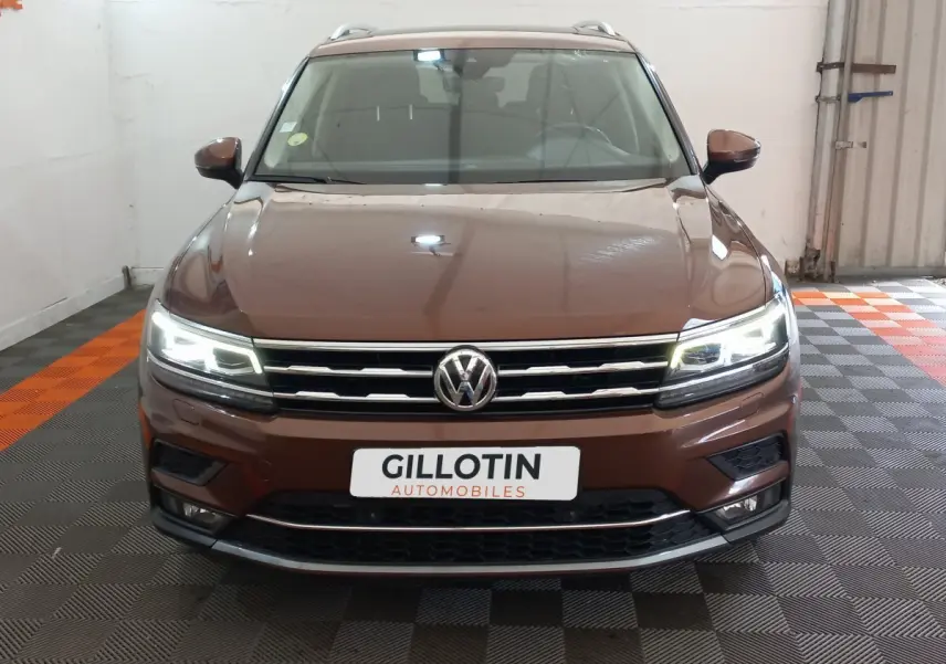 Vue frontale d'un Volkswagen Tiguan Allspace marron avec phares LED allumés dans un garage.