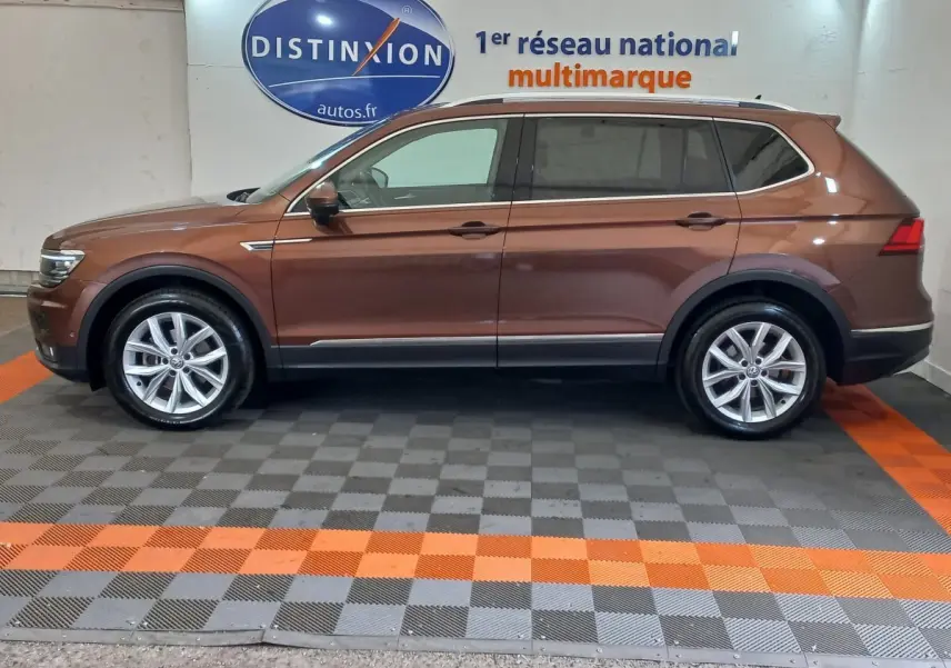 Profil côté gauche d'un Volkswagen Tiguan Allspace marron 2018 garé en intérieur sur sol gris et orange.