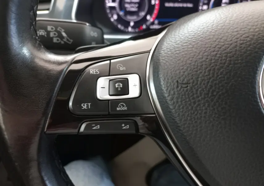 Gros plan sur les commandes du volant cuir noir du Volkswagen Tiguan Allspace 2018, avec affichage numérique en arrière-plan.